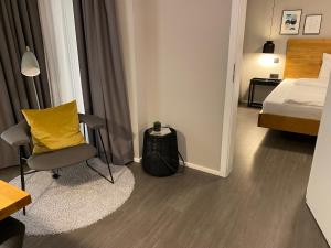 sypialnia z łóżkiem, żółtą poduszką i krzesłem w obiekcie Timehouse Serviced Apartments w Monachium