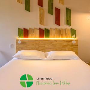 a white bed with a sign on the back of it at Hotel Nacional Inn Curitiba Santa Felicidade in Curitiba