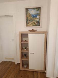 um armário branco num quarto com uma pintura na parede em Apartman Mila em Biograd na Moru