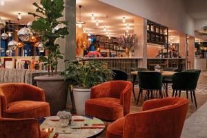 a restaurant with orange chairs and tables and plants at Hotel Berlin, Berlin, a member of Radisson Individuals in Berlin