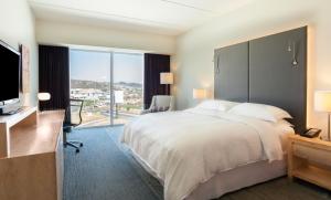 ein Hotelzimmer mit einem großen Bett und einem großen Fenster in der Unterkunft Sheraton San Jose Hotel, Costa Rica in San José