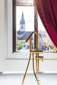 una silla de oro frente a una ventana con una iglesia en Sia Boutique Aparthotel, en Sibiu