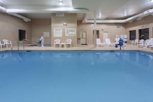 uma grande piscina com cadeiras e cadeiras brancas em Hampton Inn & Suites Astoria em Astoria, Oregon