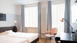 a bedroom with a white bed and a chair and windows at Hotel Schützen Rheinfelden in Rheinfelden