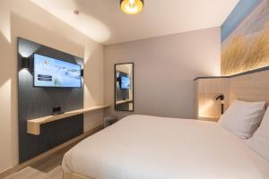 ein Hotelzimmer mit einem Bett und einem Flachbild-TV in der Unterkunft Fox Hotel The Hague Scheveningen in Scheveningen