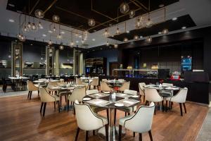 un restaurant avec des tables et des chaises ainsi qu'un bar dans l'établissement Hilton Garden Inn Krakow Airport, à Cracovie