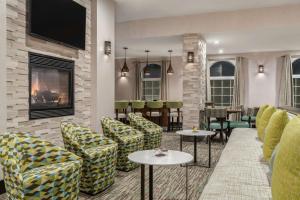 Homewood Suites by Hilton Providence-Warwick في وارويك: لوبي الفندق مع كراسي وطاولات وتلفزيون