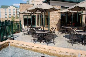 un patio avec des tables et des parasols à côté d'une piscine dans l'établissement Hilton Garden Inn Bowling Green, à Bowling Green