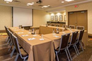 une salle de conférence avec des tables et des chaises et un tableau blanc dans l'établissement Hilton Garden Inn Charlottesville, à Charlottesville