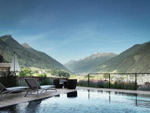 uma piscina com cadeiras e vista para as montanhas em LifestylePanoramaHotel Erika Superior em Neustift im Stubaital