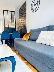 ein Wohnzimmer mit einem blauen Sofa und einer Uhr an der Wand in der Unterkunft Sweet Cēmoi Retreat in Grenoble