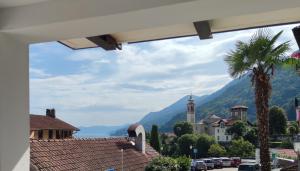 uma vista para uma cidade com uma palmeira e uma torre do relógio em Casa Ilanga em Cannero Riviera