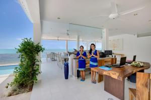 two women standing in an office with the ocean in the background at La Perle Resort Koh Samui in Mae Nam