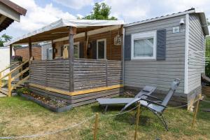 une petite maison avec une terrasse couverte et une chaise dans l'établissement Grand Mobil Home 6 personnes climatisé avec 3 chambres et 2 salles de bains à Munster en Alsace, à Munster