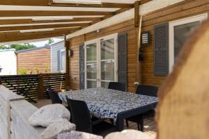 d'une terrasse avec une table et des chaises. dans l'établissement Grand Mobil Home 6 personnes climatisé avec 3 chambres et 2 salles de bains à Munster en Alsace, à Munster