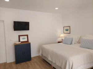 a bedroom with two beds and a flat screen tv at Estúdio Lagoa Azul in Vila Nova de Milfontes