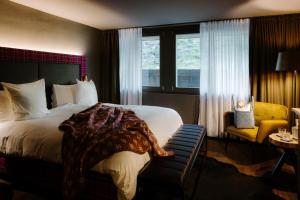 um quarto de hotel com uma cama e uma cadeira e uma janela em Bergwelt Grindelwald - Alpine Design Resort em Grindelwald