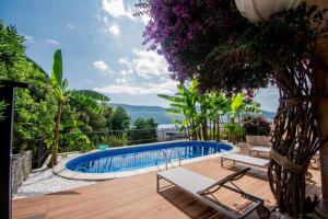 - une piscine avec 2 chaises longues sur une terrasse en bois dans l'établissement Vila Oliva, à Herceg-Novi