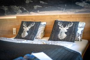 Una cama con dos almohadas con cabezas de ciervo. en Apartment Charly, en Kaprun