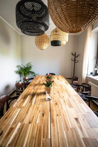 une grande table en bois avec des chaises et des lampes suspendues dans l'établissement Hotel i Restauracja Czarny Kos, à Borkowo