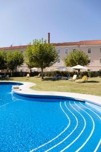 einem großen Pool mit blauem Wasser vor einem Gebäude in der Unterkunft Hotel Termas da Curia in Curia