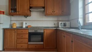 a kitchen with wooden cabinets and a stove top oven at Apartamentos Naturalis in Vila Nova de Milfontes