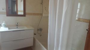 a bathroom with a sink and a shower with a mirror at Apartamentos Naturalis in Vila Nova de Milfontes