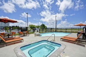 uma piscina com cadeiras e uma mesa e guarda-sol em Hilton Garden Inn Gulfport - Biloxi Airport em Gulfport