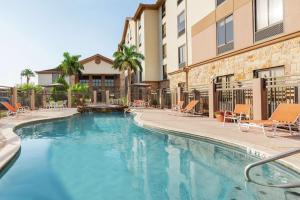 une piscine avec des chaises et un bâtiment dans l'établissement Hampton Inn and Suites Houston Clear Lake NASA, à Webster