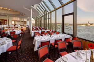 a restaurant with white tables and red chairs and windows at Hilton Mainz in Mainz