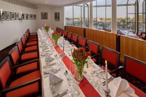 a long table in a restaurant with red chairs at Hilton Mainz in Mainz