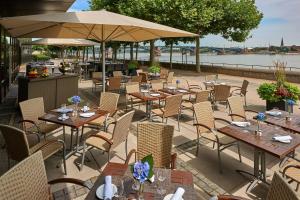 an outdoor restaurant with tables and chairs and a river at Hilton Mainz in Mainz