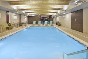 a large swimming pool in a room with chairs and tables at Home2 Suites By Hilton Holland in Holland