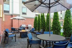 eine Terrasse mit Tischen, Stühlen und einem Sonnenschirm in der Unterkunft Hampton Inn & Suites Kittery in Kittery