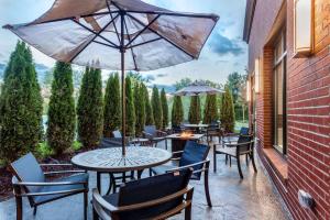 eine Terrasse mit Tischen, Stühlen und einem Sonnenschirm in der Unterkunft Hampton Inn & Suites Kittery in Kittery