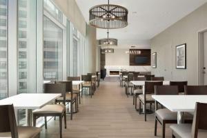 une salle à manger avec des tables et des chaises blanches dans l'établissement Homewood Suites By Hilton Chicago Downtown South Loop, à Chicago