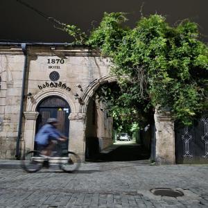 mężczyzna jeżdżący rowerem obok budynku z łukiem w obiekcie 1870 Hotel w Kutaisi