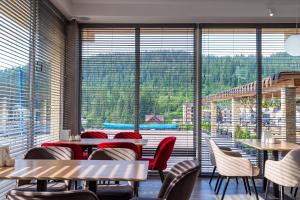 un restaurante con mesas y sillas y una gran ventana en Gold Palace SPA Resort Bukovel, en Bukovel