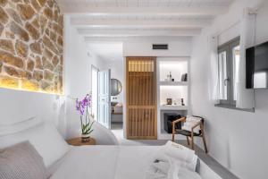 een kamer met witte muren en een stenen muur bij Legendary Suites in Mykonos-stad