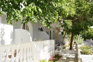 una casa blanca con una valla blanca y árboles en Skalidis Apartments, en Tolo