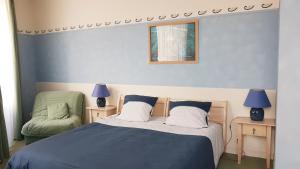 een slaapkamer met een bed en een groene stoel bij Hôtel de la Presqu'ile in Crozon