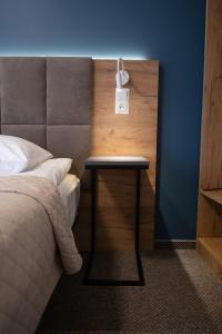 a bed with a night stand next to a side table at Hotel Halychyna in Ternopilʼ