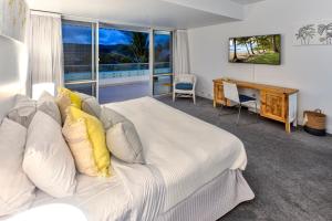 Schlafzimmer mit einem weißen Bett, einem Schreibtisch und einem Fenster in der Unterkunft Bella Vista East 4 Oceanview, Golf Buggy, Valet Service & Shared Pool in Hamilton Island