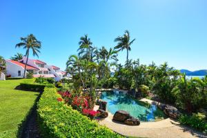 einen Pool in einem Garten mit Palmen und Blumen in der Unterkunft Bella Vista East 4 Oceanview, Golf Buggy, Valet Service & Shared Pool in Hamilton Island