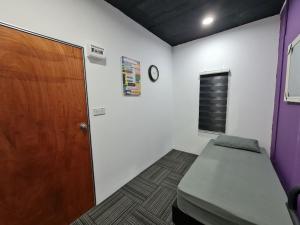 Cette chambre comprend un lit et une porte en bois. dans l'établissement Ayden Hostel Airport Transit - KLIA, à Sepang