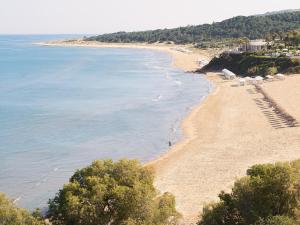 Blick auf einen Strand mit Bäumen und das Meer in der Unterkunft Grecotel LUXME Palms at Riviera Olympia & Aqua Park in Loutra Killinis