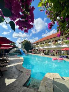 una piscina en un complejo con flores púrpuras en Marine Bay Sanur, en Sanur