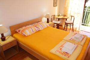 1 dormitorio con 1 cama amarilla, mesa y sillas en Guest House Tomanovic, en Herceg-Novi