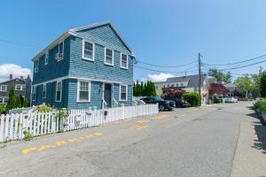 a blue house on a street with a white fence at Condo with Wading Pool Dog Welcome in Provincetown