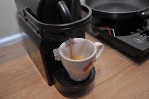 a coffee cup with a spoon inside of a toaster at Jacuzzi Apartman De Lux - Cacak in Čačak